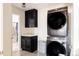 Functional laundry room with stacked washer and dryer and storage cabinets at 14537 Honolulu Cir, Parker, CO 80134