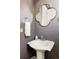 Stylish powder room featuring a decorative mirror, pedestal sink, and neutral wall color at 14537 Honolulu Cir, Parker, CO 80134