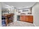 Basement bar area with custom wood bar, cabinets, beverage cooler, sink and open shelving at 5964 S Florence Ct, Englewood, CO 80111