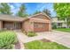 Close-up of brick home featuring a front entrance, two-car garage, and manicured landscaping at 5964 S Florence Ct, Englewood, CO 80111