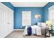 Bright blue bedroom featuring a large window, a closet, and a stylish bedside table at 3261 Trenton St, Denver, CO 80238