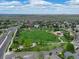 Expansive aerial view of a community park with playground and green space, framed by houses and a distant mountain range at 14675 Golden Eagle Run, Broomfield, CO 80023