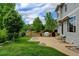 Backyard featuring a lush lawn, mature trees, and a spacious patio with a built-in grill at 14675 Golden Eagle Run, Broomfield, CO 80023