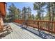 Wide wooden deck with chairs and railing, perfect for enjoying the outdoors and the serene woodland views at 21345 Cliffwoods Trl, Morrison, CO 80465