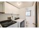 Well-equipped laundry room featuring a washer, dryer, white cabinets, and an adjacent door to the bathroom at 2603 W 100Th Pl, Denver, CO 80260