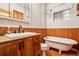 Bathroom vanity with granite counter, classic clawfoot tub, and wood paneling at 5094 Meade St, Denver, CO 80221