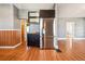 Kitchen area with stainless steel refrigerator and wood floors adjacent to dining and living space at 5094 Meade St, Denver, CO 80221