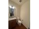 Well-lit powder room with granite counter, wood cabinet and a white toilet at 14241 Ivanhoe St, Thornton, CO 80602