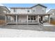 Backyard with a covered porch, lots of seating, and gravel landscaping in a snowy setting at 2598 Knobbie Cir, Castle Rock, CO 80109