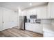 Bright kitchen features stainless steel refrigerator, white cabinets, white quartz counters, and wood look flooring at 2598 Knobbie Cir, Castle Rock, CO 80109