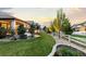 Expansive backyard with manicured lawn, stone accents, and charming white fence provides a serene outdoor setting at 10660 Winding Pine Pt, Highlands Ranch, CO 80126