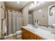 Well-lit bathroom with a wood vanity, large mirror, and tile shower with neutral tones at 10660 Winding Pine Pt, Highlands Ranch, CO 80126