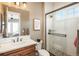 Bathroom with a white subway tile shower, wood vanity and stone-look floor at 10660 Winding Pine Pt, Highlands Ranch, CO 80126