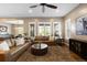 Cozy living room with large windows, a ceiling fan, hardwood floors, and leather sofas at 10660 Winding Pine Pt, Highlands Ranch, CO 80126