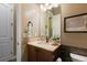 Powder room with a wood vanity, stone countertop and decorative mirror at 10660 Winding Pine Pt, Highlands Ranch, CO 80126
