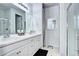 Well-lit bathroom with double sinks, white cabinets, and a glass-enclosed shower at 802 Eva Peak Dr, Erie, CO 80516
