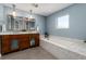 Bathroom featuring double sinks, mirrors, and a soaking tub with elegant tile surround at 1385 Birch St, Denver, CO 80220