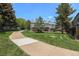 Exterior view of the home featuring a manicured lawn, trees, and nearby sidewalk at 1919 Newland Ct, Lakewood, CO 80214