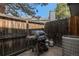 A cozy patio area with wooden fence, grill, propane tanks, and AC unit for outdoor enjoyment at 1919 Newland Ct, Lakewood, CO 80214