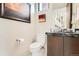 Powder room with marble countertop, dark wood vanity, modern fixtures, and framed artwork at 1717 Irving St, Denver, CO 80204