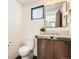 A powder room featuring a modern vanity with stone countertop, a sleek mirror, and a toilet at 1717 Irving St, Denver, CO 80204