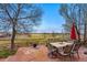 Outdoor patio features a stone tile floor with a table and seating with a grassy yard and open field in the background at 13686 Dexter St, Thornton, CO 80602