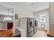Well-lit laundry room featuring modern washer and dryer units with folding table, and exterior door at 13686 Dexter St, Thornton, CO 80602