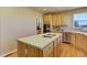 A bright kitchen offers a large island with cooktop, wooden cabinets, and hardwood floors at 10169 Briargrove Way, Highlands Ranch, CO 80126