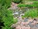Babbling brook over rocks and stone. Surrounded by lush greenery at 2700 E Cherry Creek S Dr # 302, Denver, CO 80209
