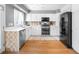 Well-lit kitchen featuring stainless steel appliances, white cabinets, and hardwood floors at 5174 W 123Rd Pl, Broomfield, CO 80020