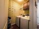 Laundry room with patterned walls, cabinetry, washer and dryer units, and wood flooring at 541 Park Blvd, Brighton, CO 80603