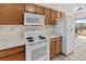 A view of the kitchen featuring wooden cabinets and white appliances including a stove, microwave and refrigerator at 800 W Belleview Ave # 201, Englewood, CO 80110