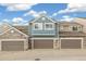 Townhome exterior featuring blue siding, stone accents, and attached garages under a blue sky at 11386 Grove St # B, Westminster, CO 80031