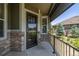 Inviting front porch with a stone facade, leading to the front door with an added storm door at 25019 E Alder Dr, Aurora, CO 80016