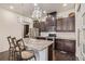 Modern kitchen with granite countertops, dark wood cabinets, stainless steel appliances, and an island with barstools at 25019 E Alder Dr, Aurora, CO 80016