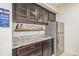 A fully functional wet bar features cabinetry, granite counters, sink, and a stainless steel refrigerator at 25019 E Alder Dr, Aurora, CO 80016