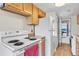 Compact kitchen features white appliances including a range and refrigerator, light wood cabinets, and an exterior door at 7933 Chase Cir # 182, Arvada, CO 80003