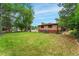 Expansive green backyard, bordered by mature trees offers space for recreation and outdoor activities at 8675 Calvin Dr, Arvada, CO 80002