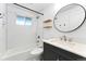 Bright bathroom with subway tile shower, modern vanity, and a sleek, round mirror at 8675 Calvin Dr, Arvada, CO 80002