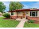 Inviting front entrance featuring brick accents, a well-manicured lawn, and a wood-stained door at 8675 Calvin Dr, Arvada, CO 80002