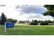 Scenic view of Wolff Park featuring a playground, green grass, and shade trees on a partly cloudy day at 8675 Calvin Dr, Arvada, CO 80002