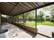 An outdoor covered patio flows into a large grassy backyard with mature trees and a privacy fence at 2415 Pontiac St, Denver, CO 80207