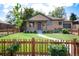 Charming brick home featuring a well-manicured lawn and a classic wooden picket fence at 2415 Pontiac St, Denver, CO 80207