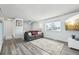 Living room with gray couch, gray laminate floors, and access to hallway at 6094 S Dudley Way, Littleton, CO 80123