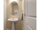 Chic powder room featuring a pedestal sink, oval mirror, and neutral color palette providing a clean and modern look at 18061 E Saskatoon Pl, Parker, CO 80134