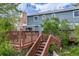 Backyard wooden deck with stairs and outdoor seating featuring a pink umbrella and well-maintained landscaping at 9926 W Nova Pl, Littleton, CO 80127