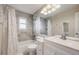 Well-lit bathroom featuring gray tiled walls, a shower-tub combo, and a large, modern vanity at 9926 W Nova Pl, Littleton, CO 80127