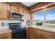 Well-lit kitchen with wood cabinets, a modern microwave and stove, and a view of the outdoors at 10963 N Chatfield Dr, Littleton, CO 80125