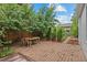 Backyard patio with a brick surface and a wooden dining table, surrounded by lush greenery at 360 S Ogden St, Denver, CO 80209