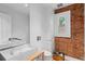 Modern bathroom featuring dual sinks, a toilet and brick accent wall next to a window at 360 S Ogden St, Denver, CO 80209